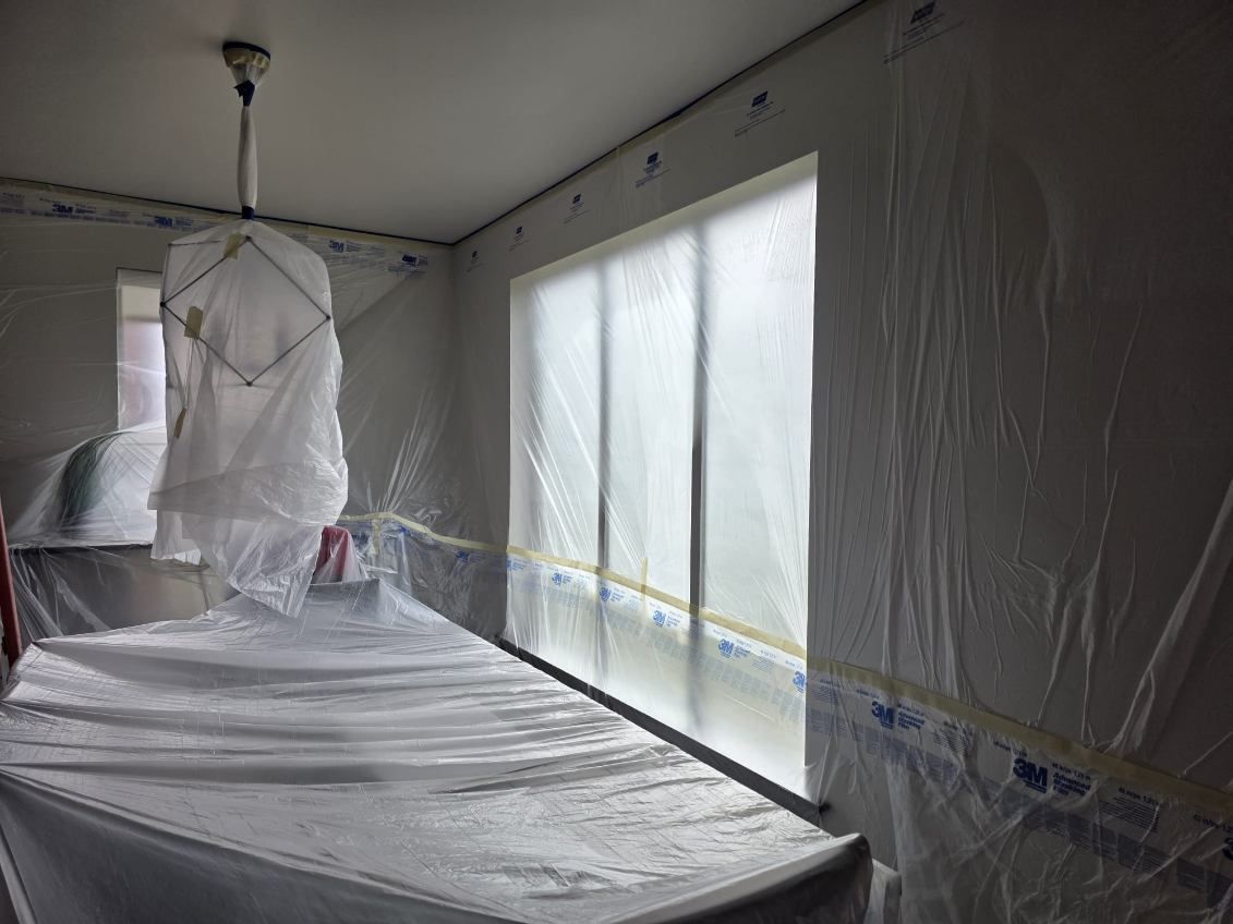 A room with a table and windows covered in plastic.
