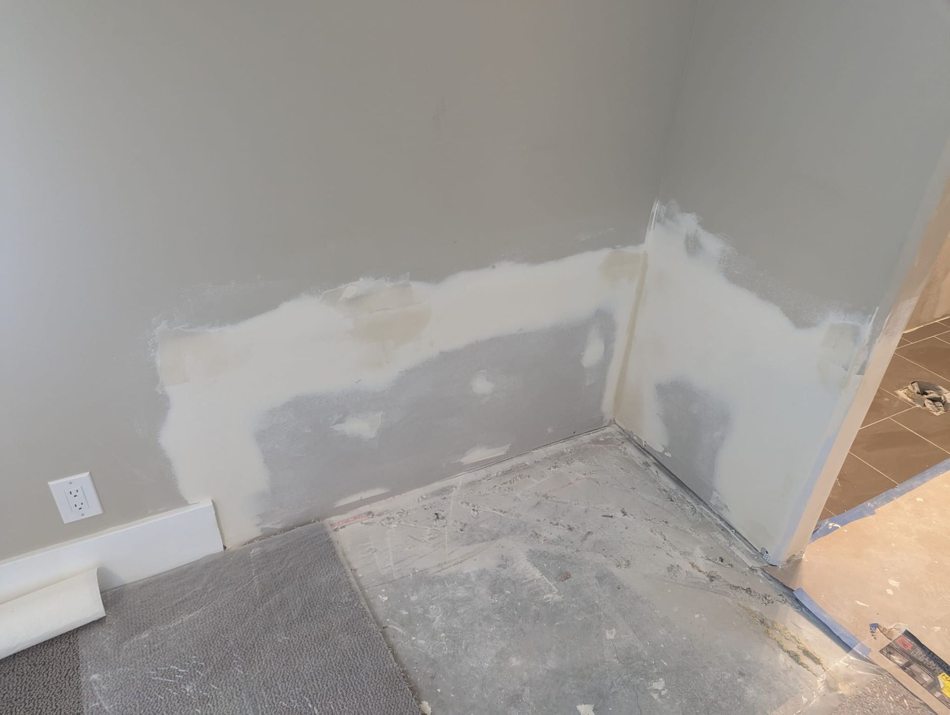 A room with a carpeted floor and a wall that is being painted.