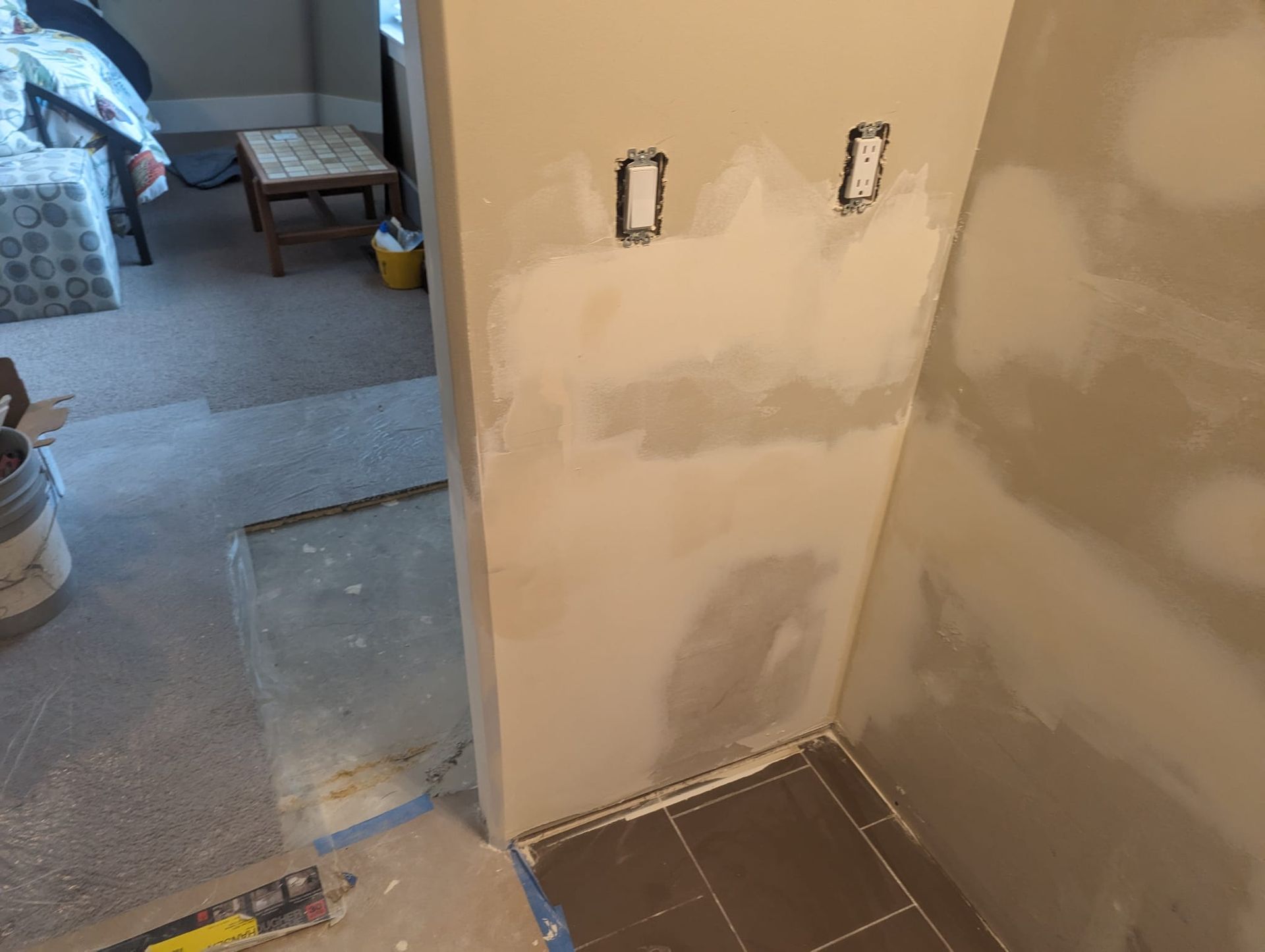 A room that is being remodeled with tile floors and a couch in the background.