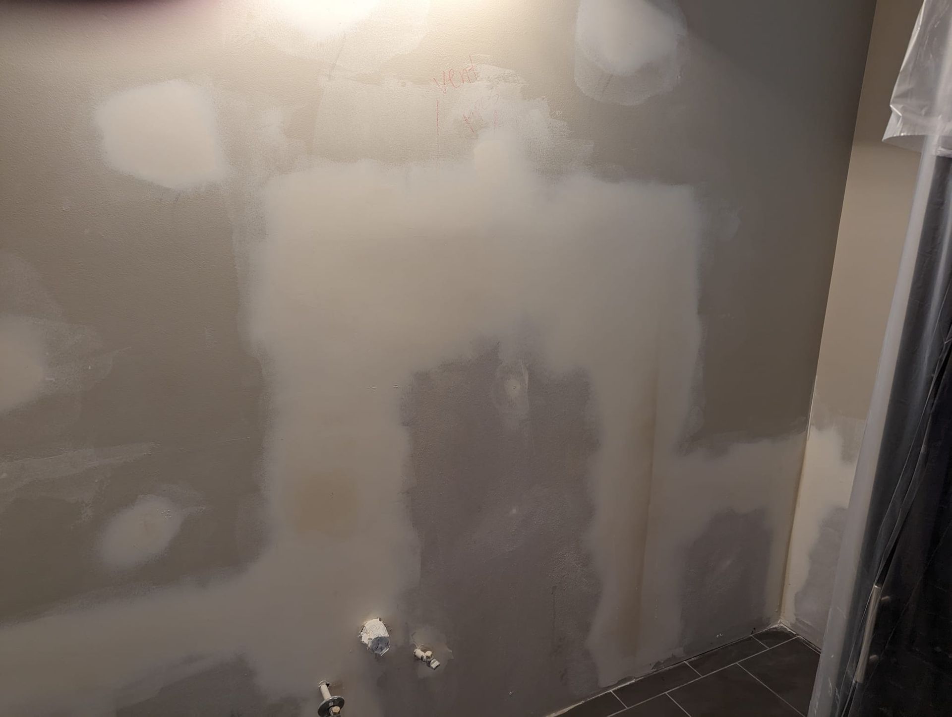 A person is standing in front of a wall that is being painted.