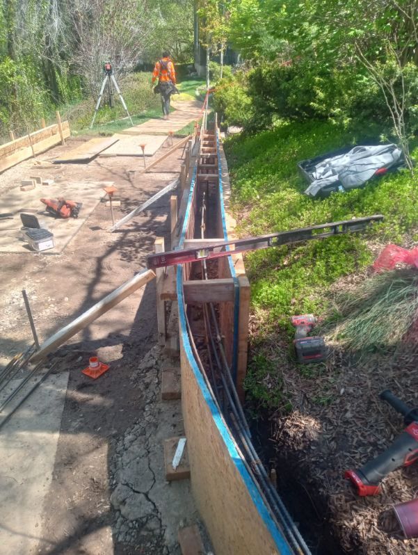 A man is working on a concrete wall in a yard.