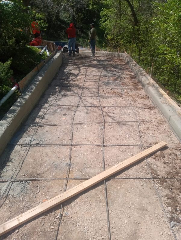 A concrete walkway with a wooden plank on the ground