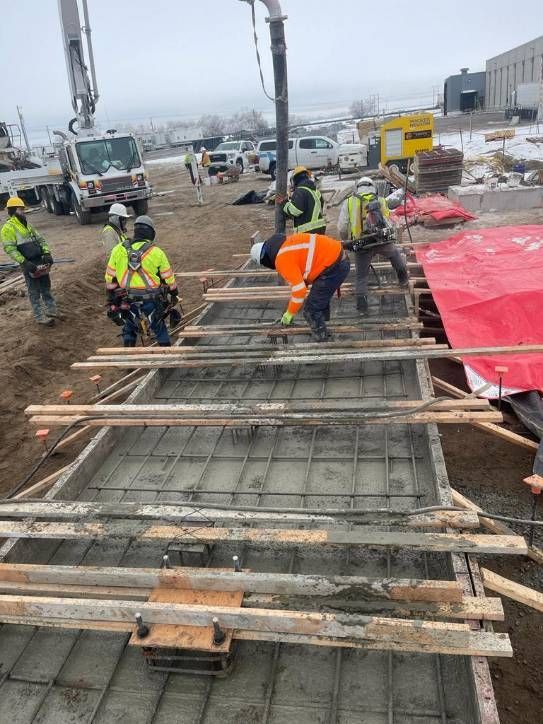 A group of construction workers are working on a concrete floor.