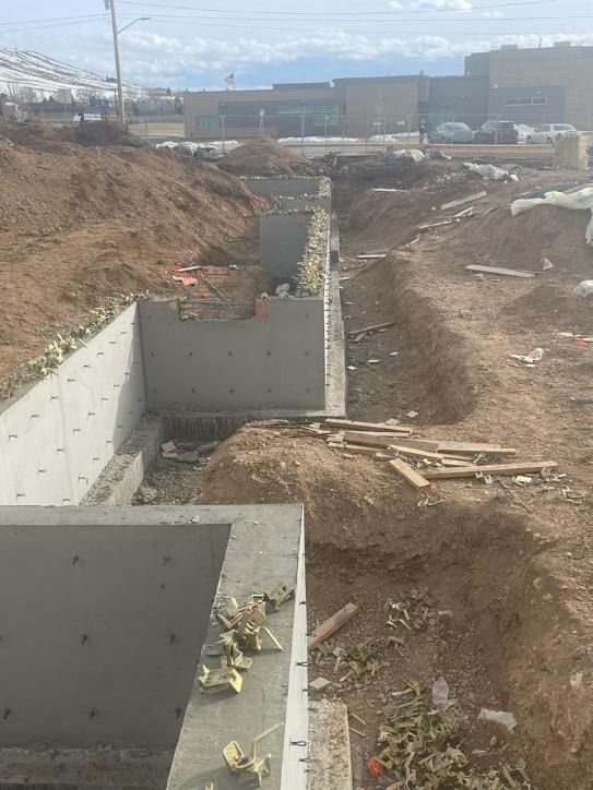 A concrete foundation is being built in a dirt field.