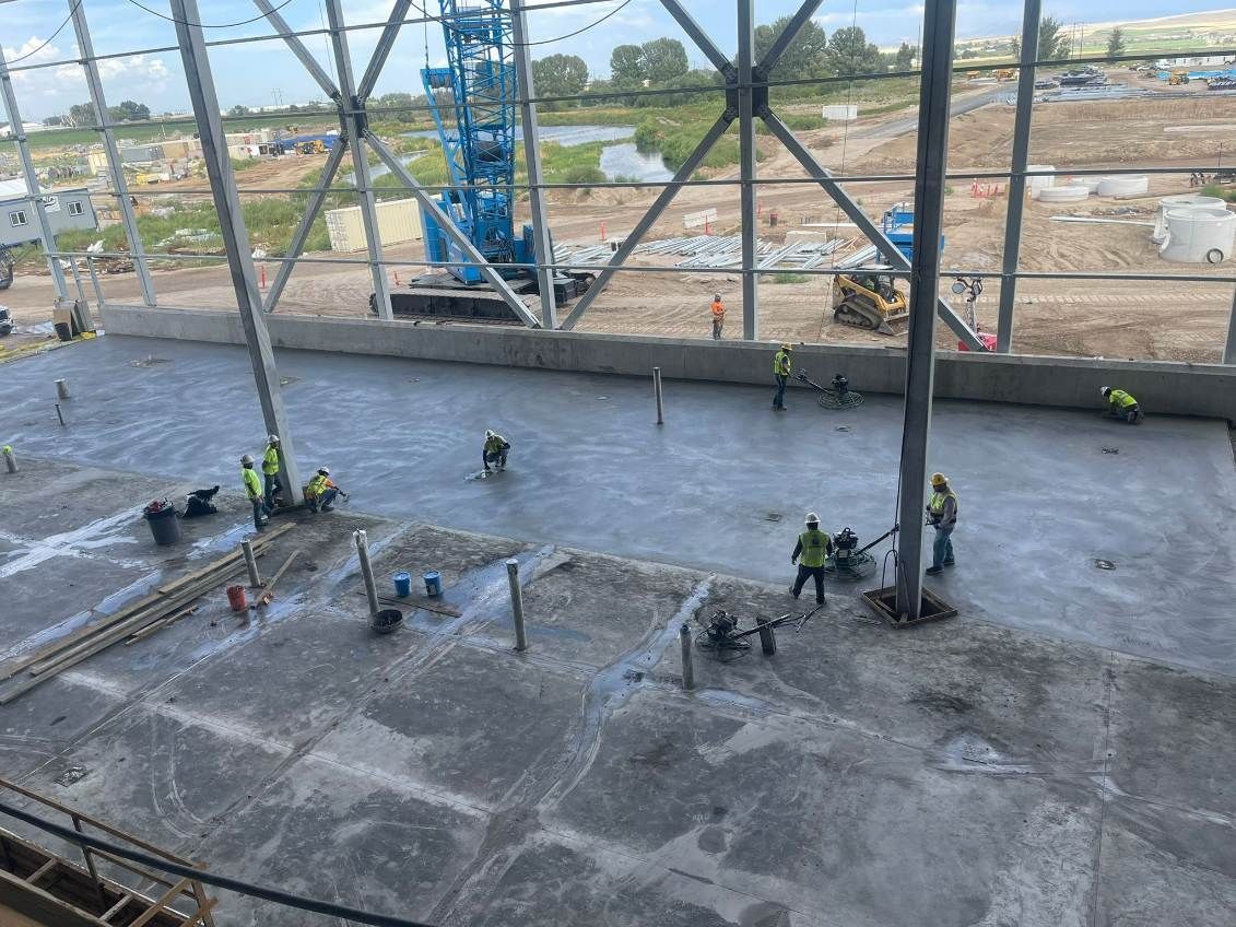 A group of construction workers are working on a concrete floor.