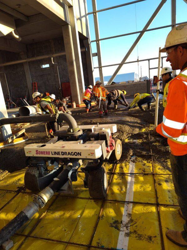 A group of construction workers are working on a concrete floor