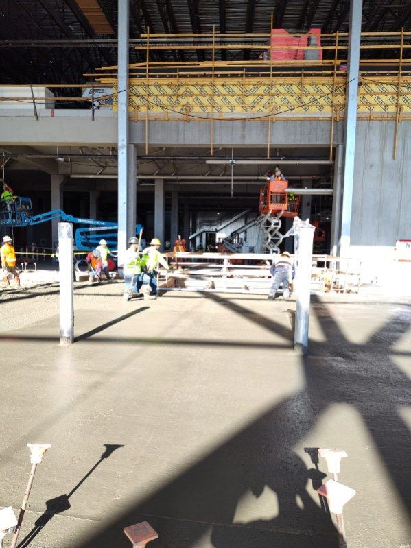 A group of construction workers are working on a concrete floor