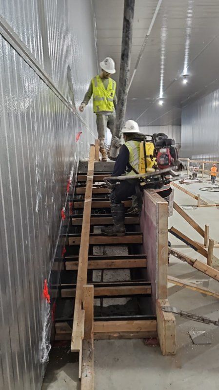 Two construction workers are walking up a set of wooden stairs.