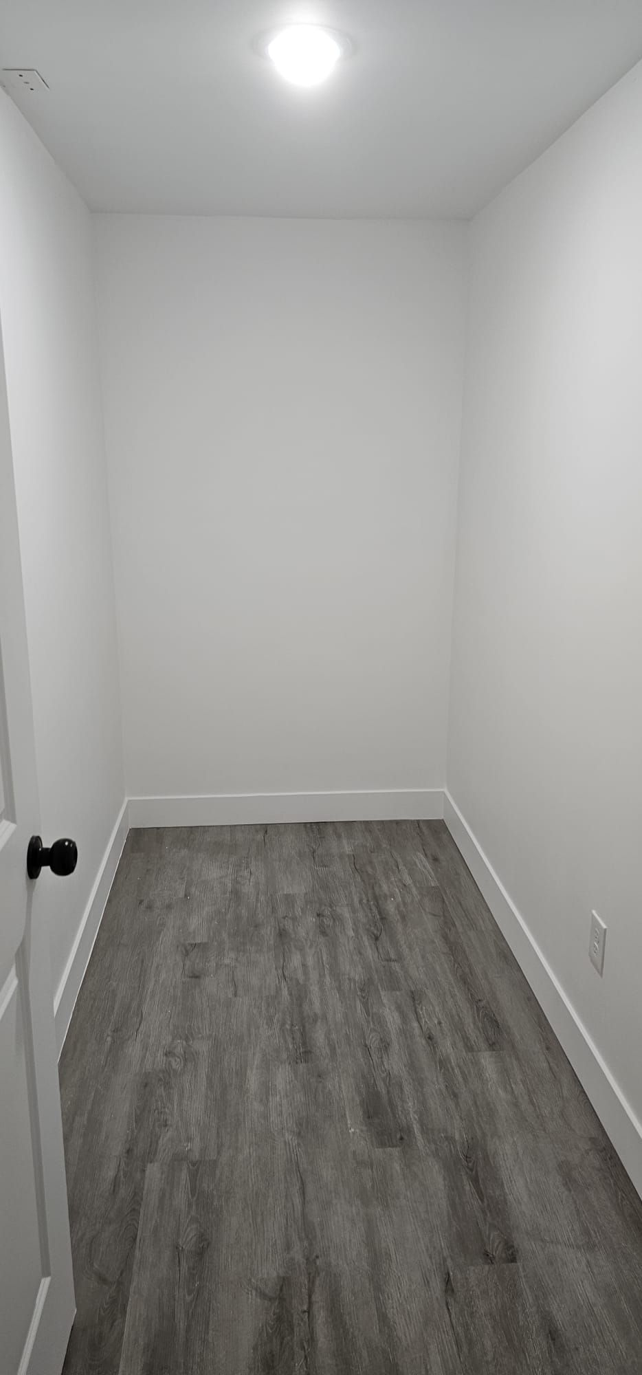 An empty room with hardwood floors and white walls.
