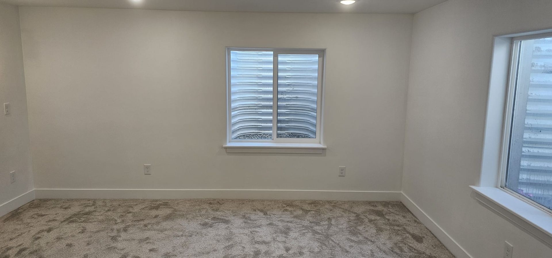 An empty room with a window and a carpeted floor.