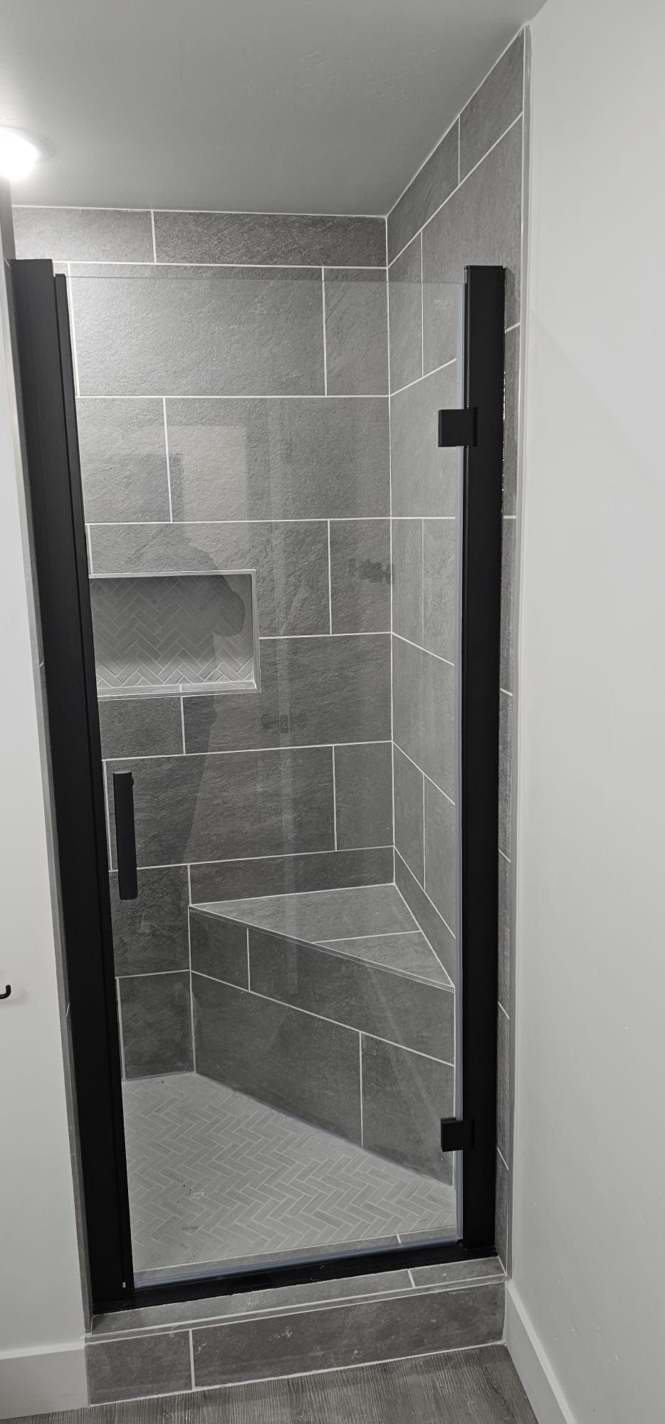 A black and white photo of a shower with a glass door.