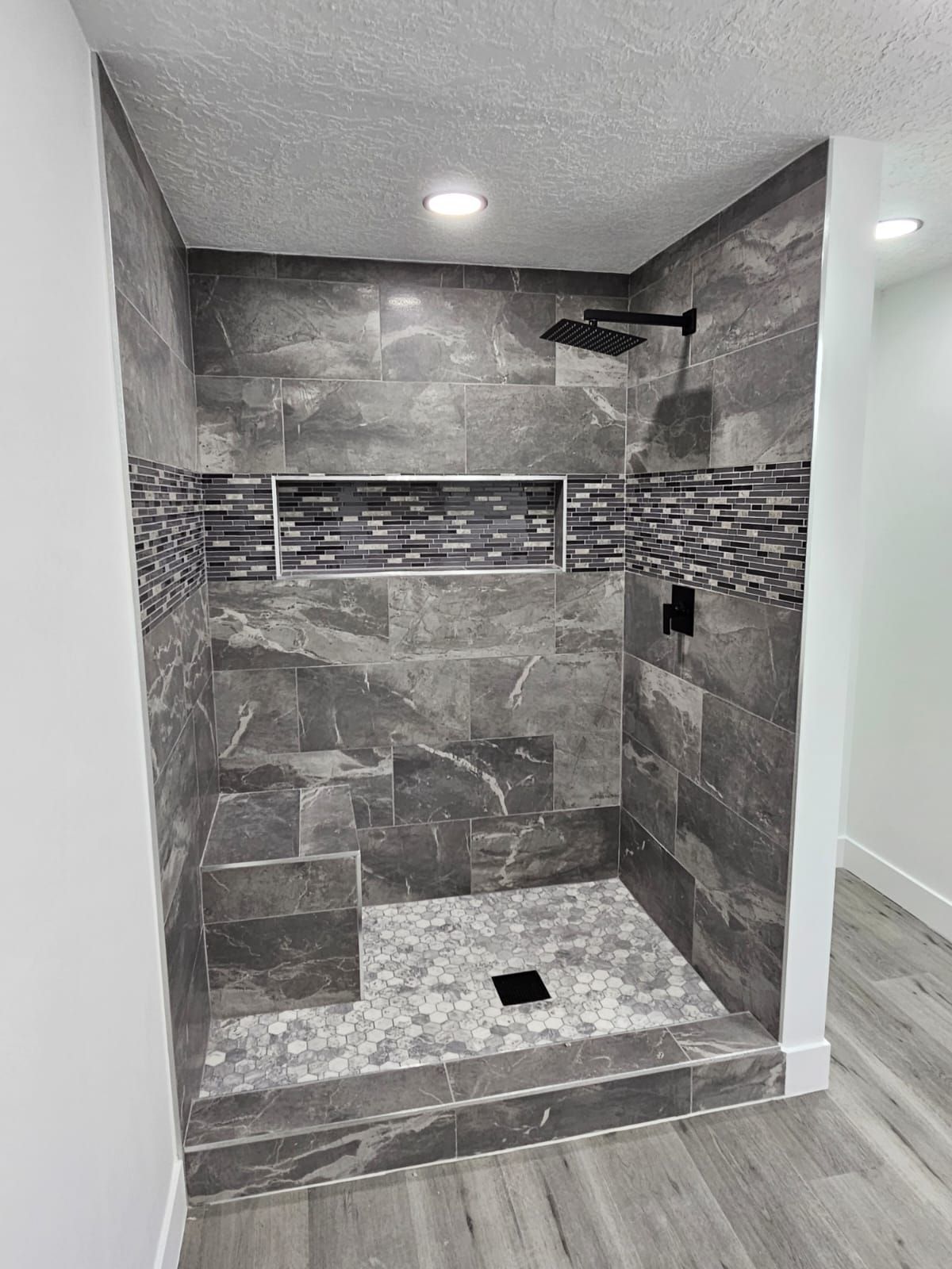 A bathroom with a walk in shower and a shower head.