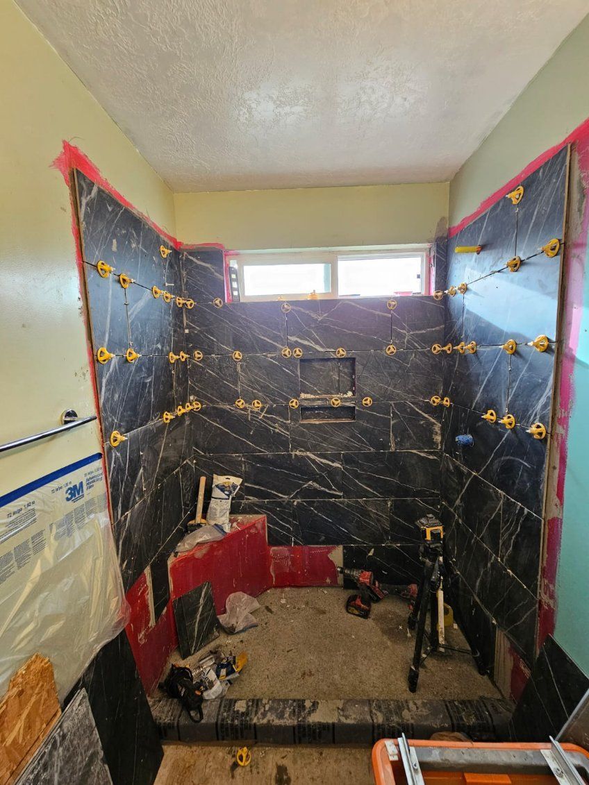 A bathroom is being remodeled with tile and a window.