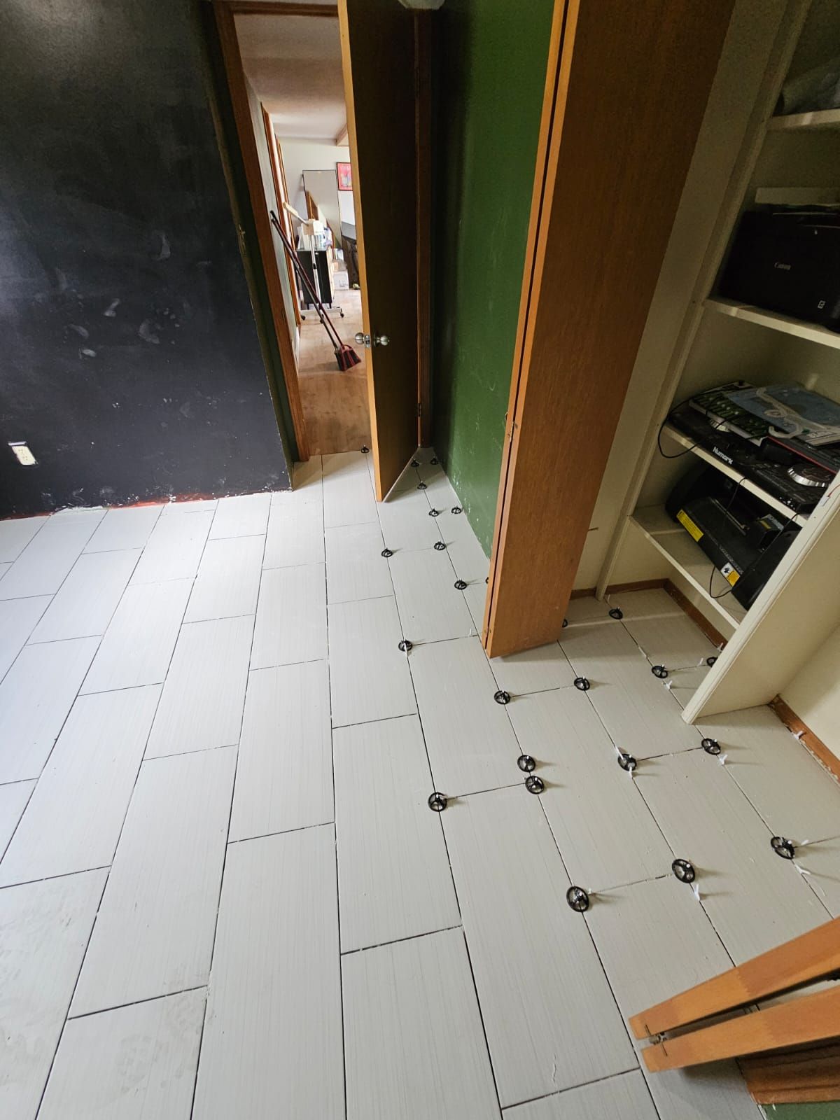 A hallway with white tiles and a green wall