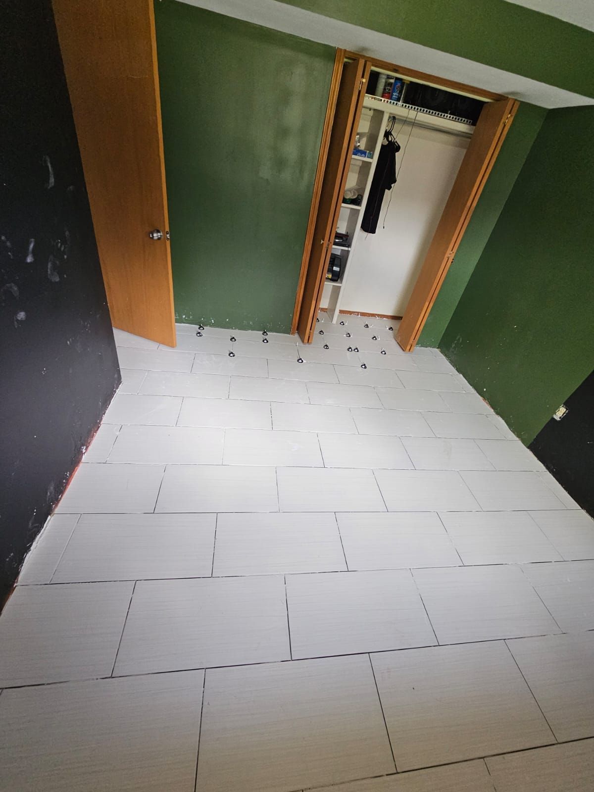 A room with green walls and white tile floors