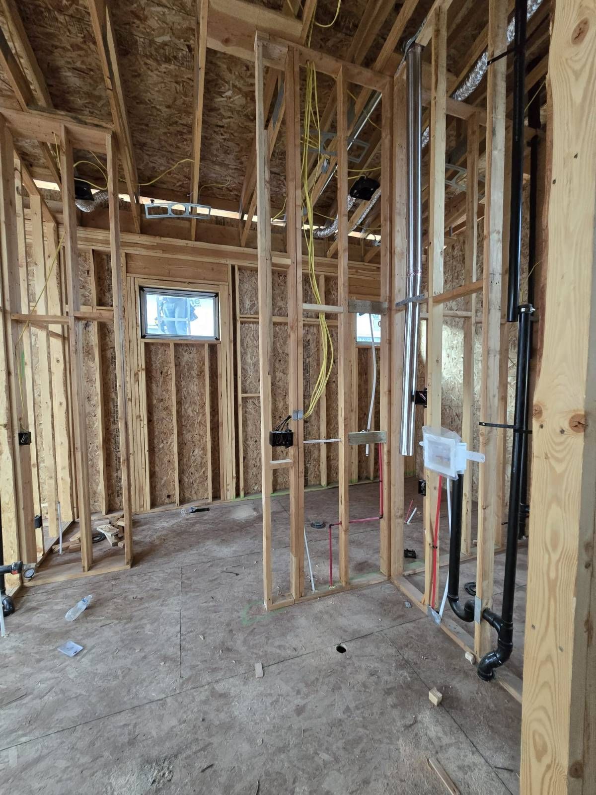 A room in a house under construction with wooden beams and pipes.
