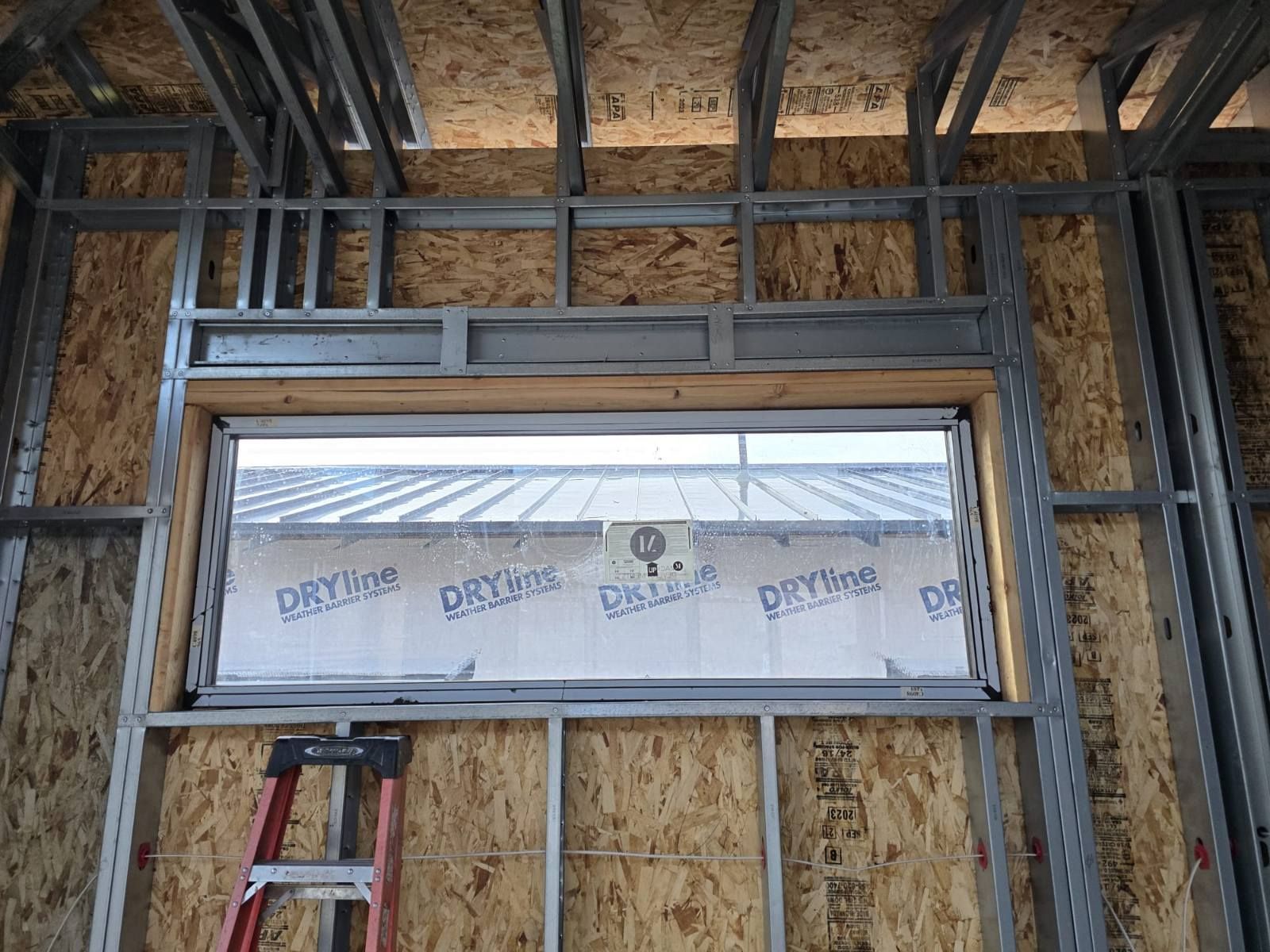 A ladder is sitting next to a window in a building under construction.