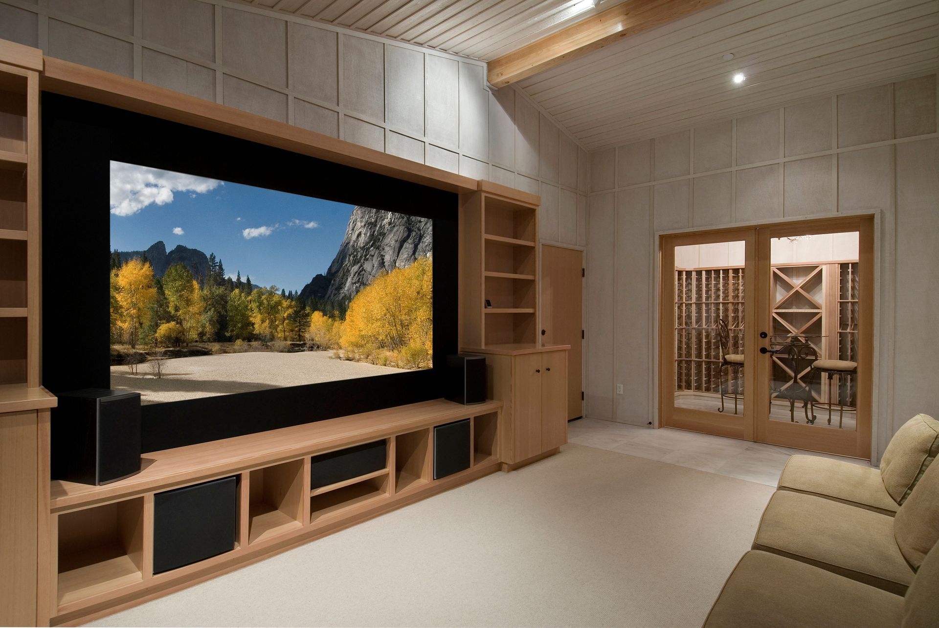 Modern living room with a large TV displaying a mountain landscape and built-in wood shelving