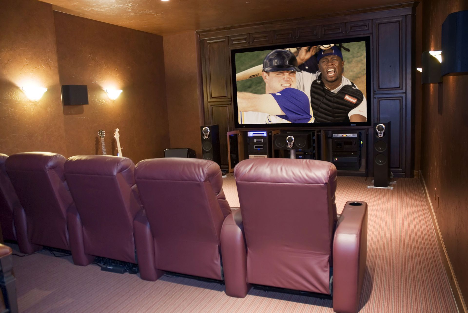 Home theater with purple recliners facing a large screen showing two people talking