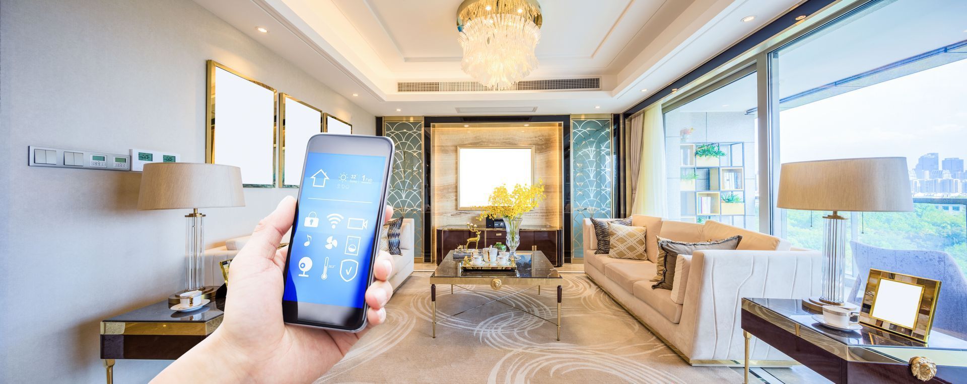 Hand holding smartphone in a bright living room with sofa, chandelier, and large windows