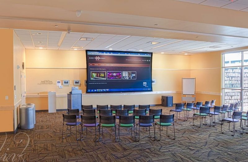 Empty conference room with rows of chairs facing a large presentation screen