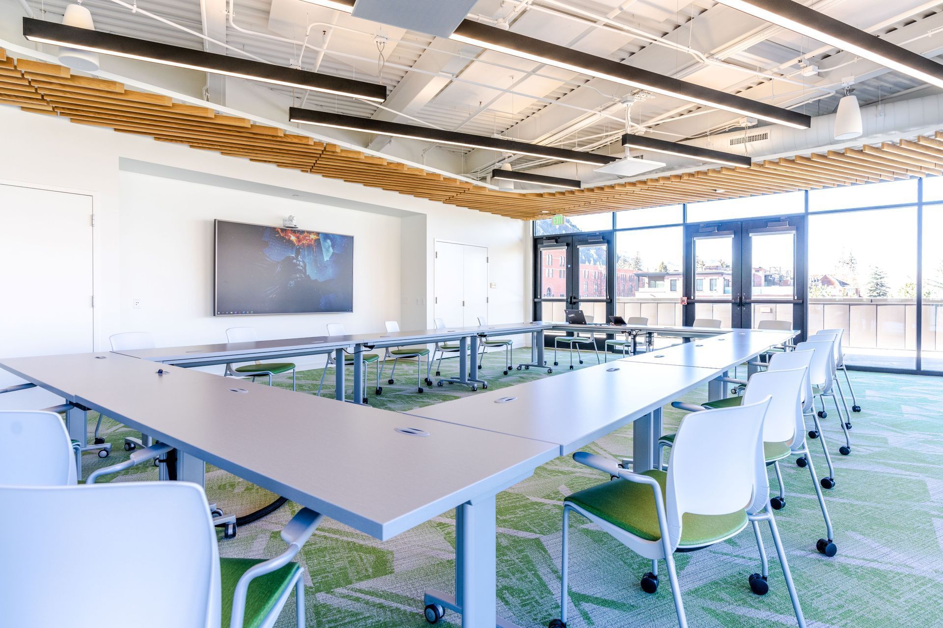 Modern conference room with white chairs, glass table, and bright windows
