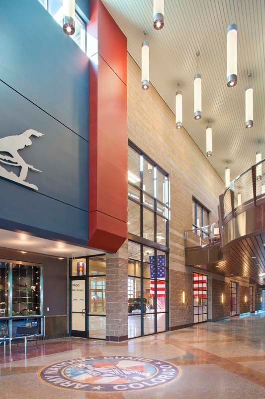 Modern atrium lobby with tall windows, hanging lights, and a red and blue wall mural