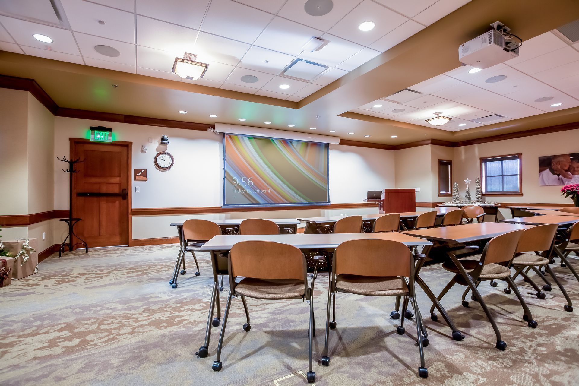Conference room with rows of chairs and long tables, colorful wall art, and ceiling lights