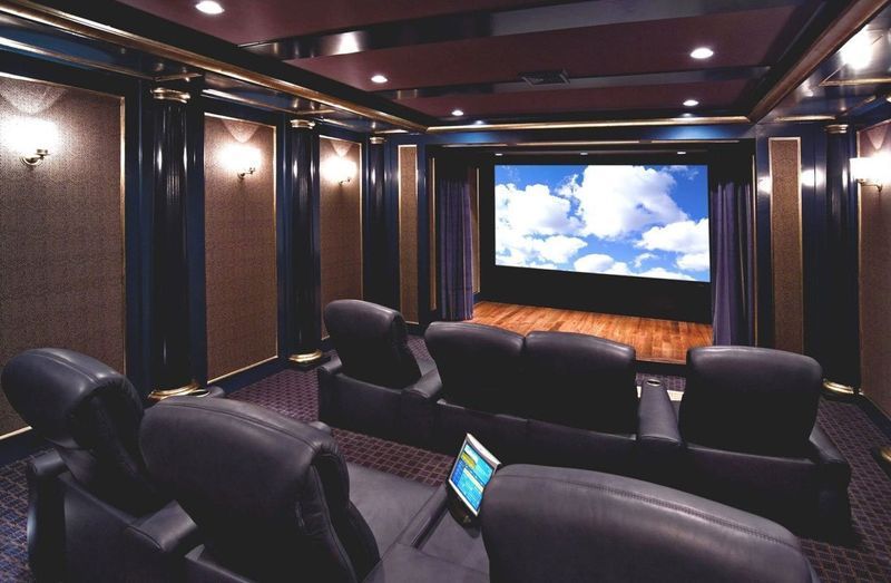 Luxury home theater with leather recliners and a large screen showing a cloudy sky