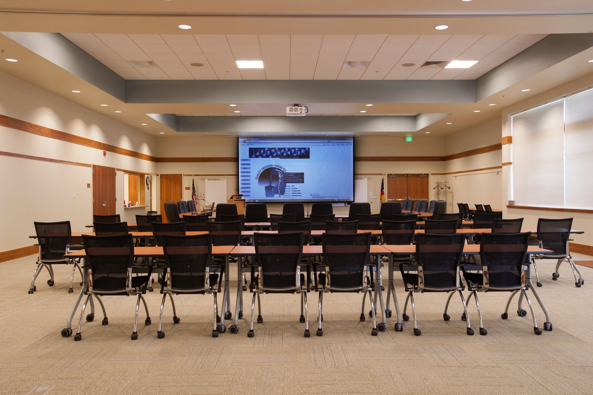 Empty conference room with rows of chairs facing a presentation screen at the front