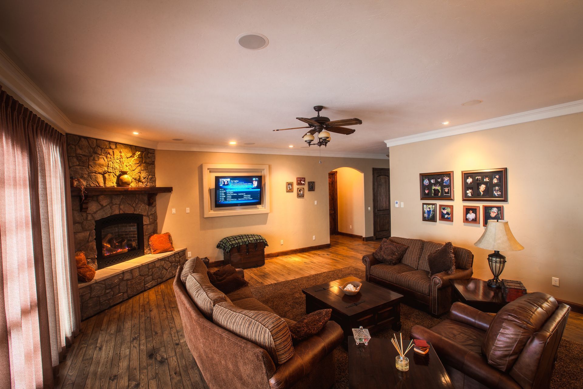 Cozy living room with fireplace, brown leather chairs, wall-mounted TV, and warm beige decor