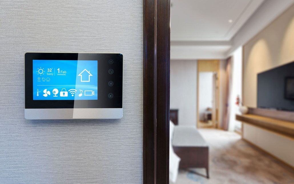 Wall-mounted smart home control panel beside a hallway opening into a modern living room