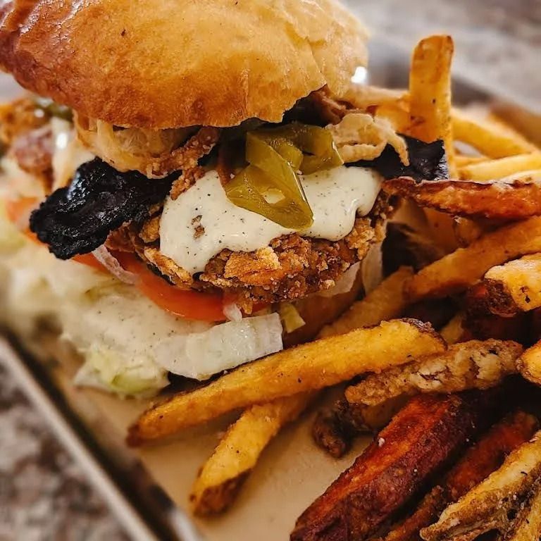 Burger with fried patty, jalapeños, and crispy onions served with fries.