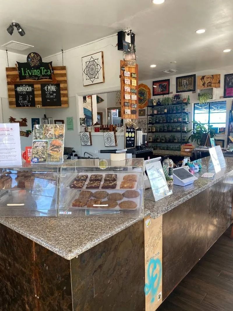 Interior of a shop with a display case of baked goods and merchandise on shelves.