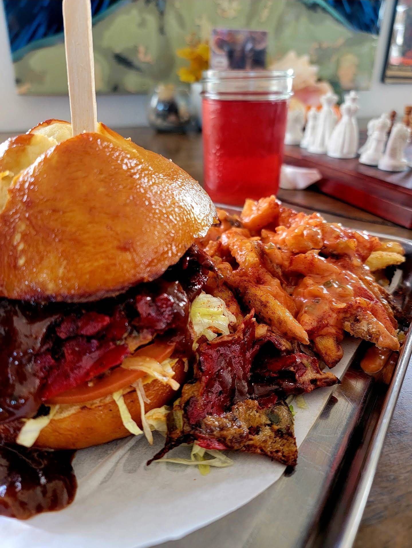 Burger with sweet potato fries and red drink.