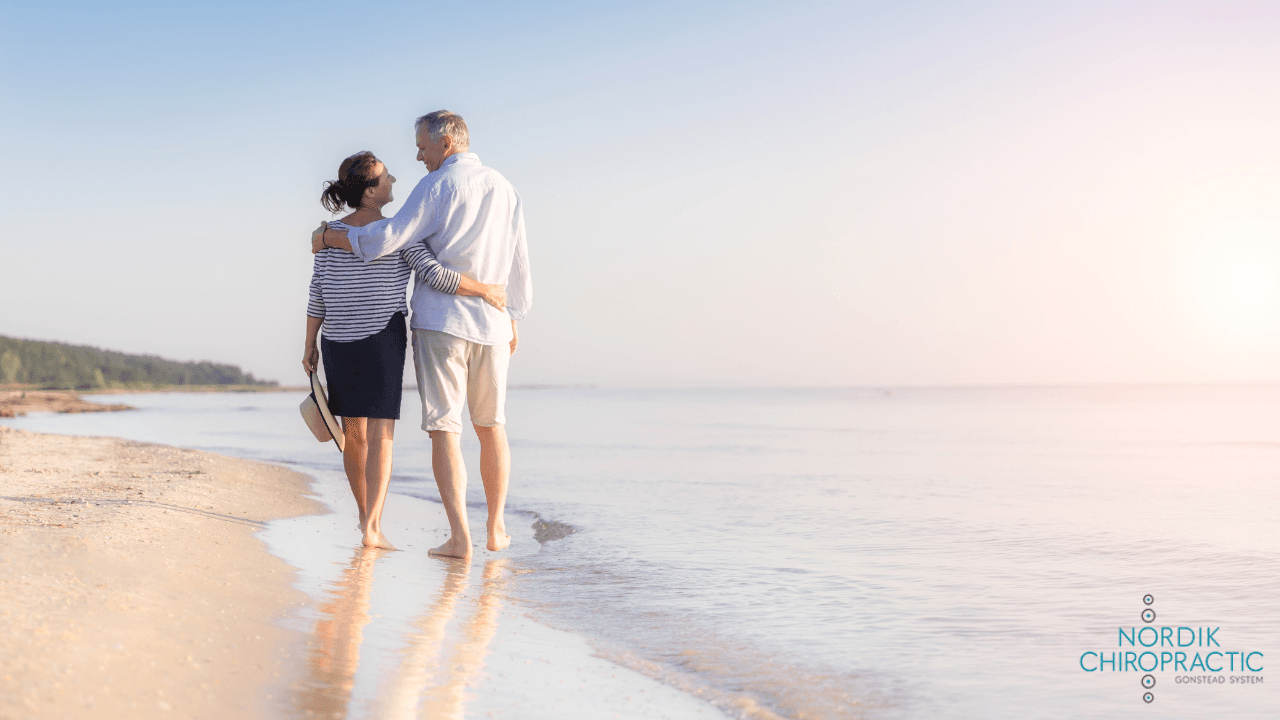 Two people walking hand in hand along a calm beach at sunrise