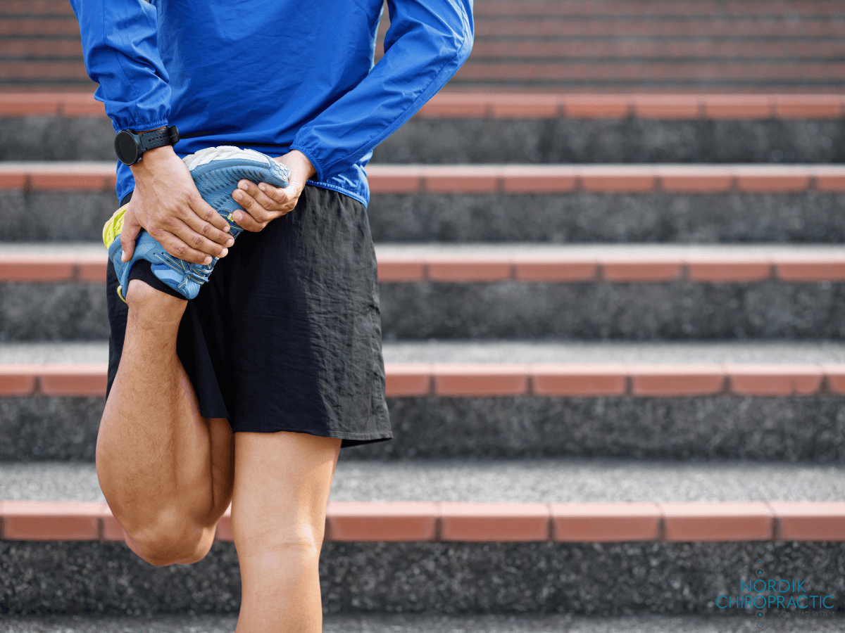 Person stretching hamstring on outdoor stairs, holding one foot behind the body.