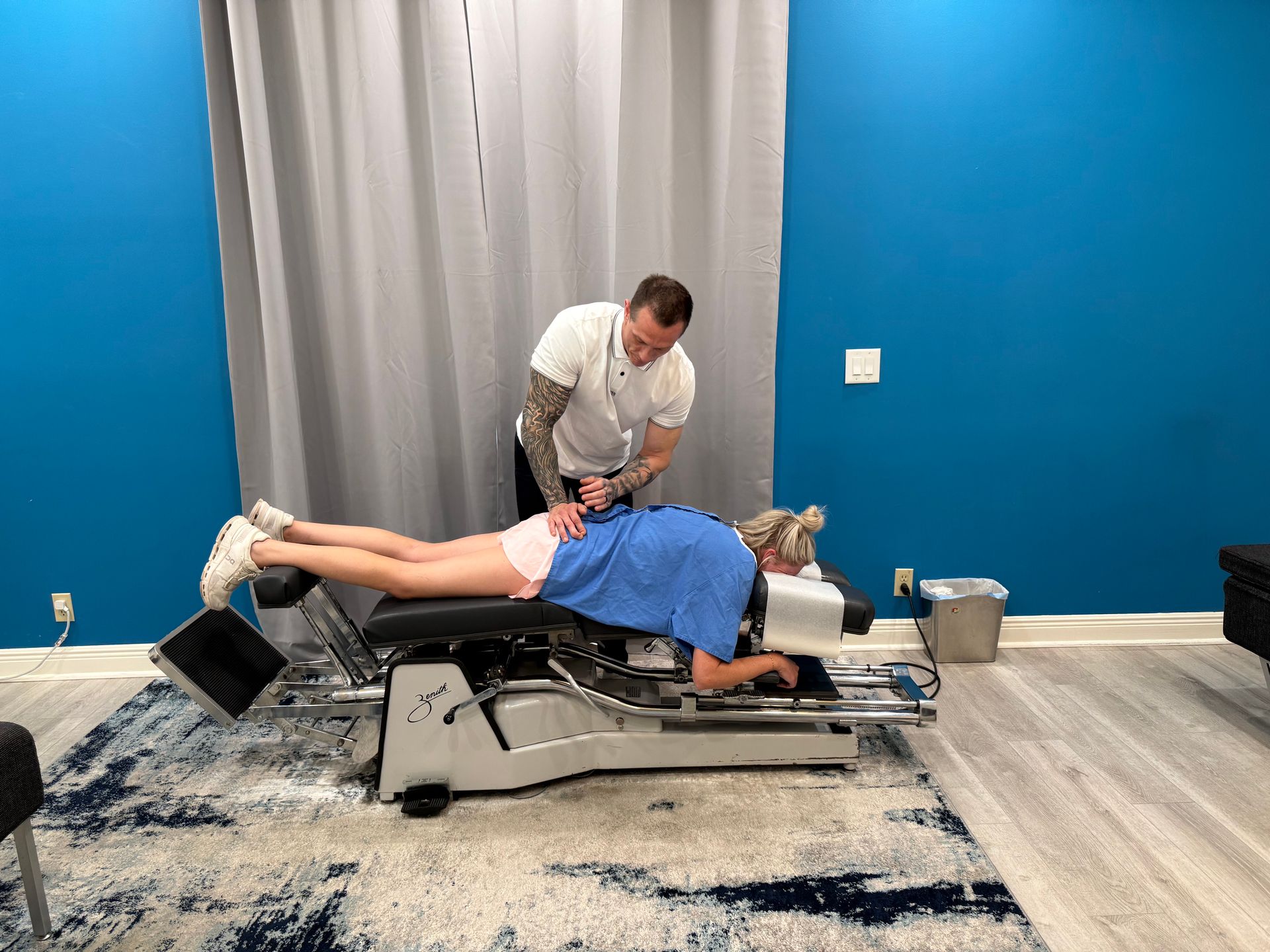 Person receiving assisted exercise on a Pilates reformer in a blue-walled studio