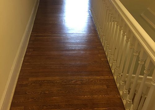 Hallway with stained hardwood floor and white balustrade.