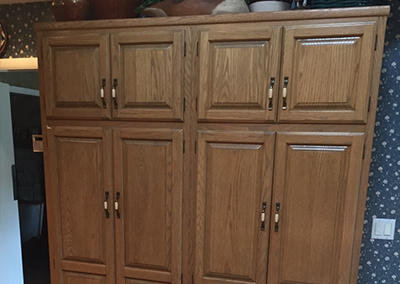 Wooden kitchen pantry cabinet with eight doors, set against a star-patterned wallpaper.