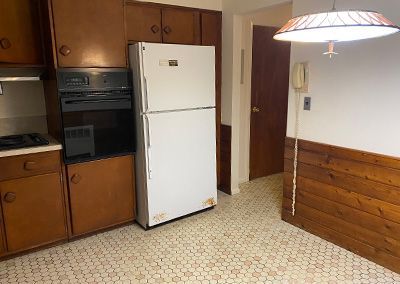Kitchen with brown cabinets, white refrigerator, and hexagonal floor tiles.