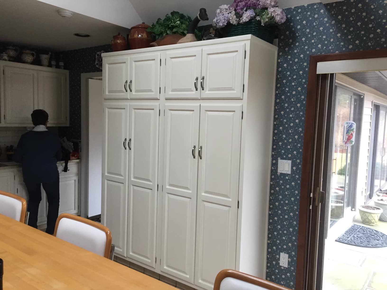 Kitchen with large white cabinets, a person, and a view of an outdoor patio.