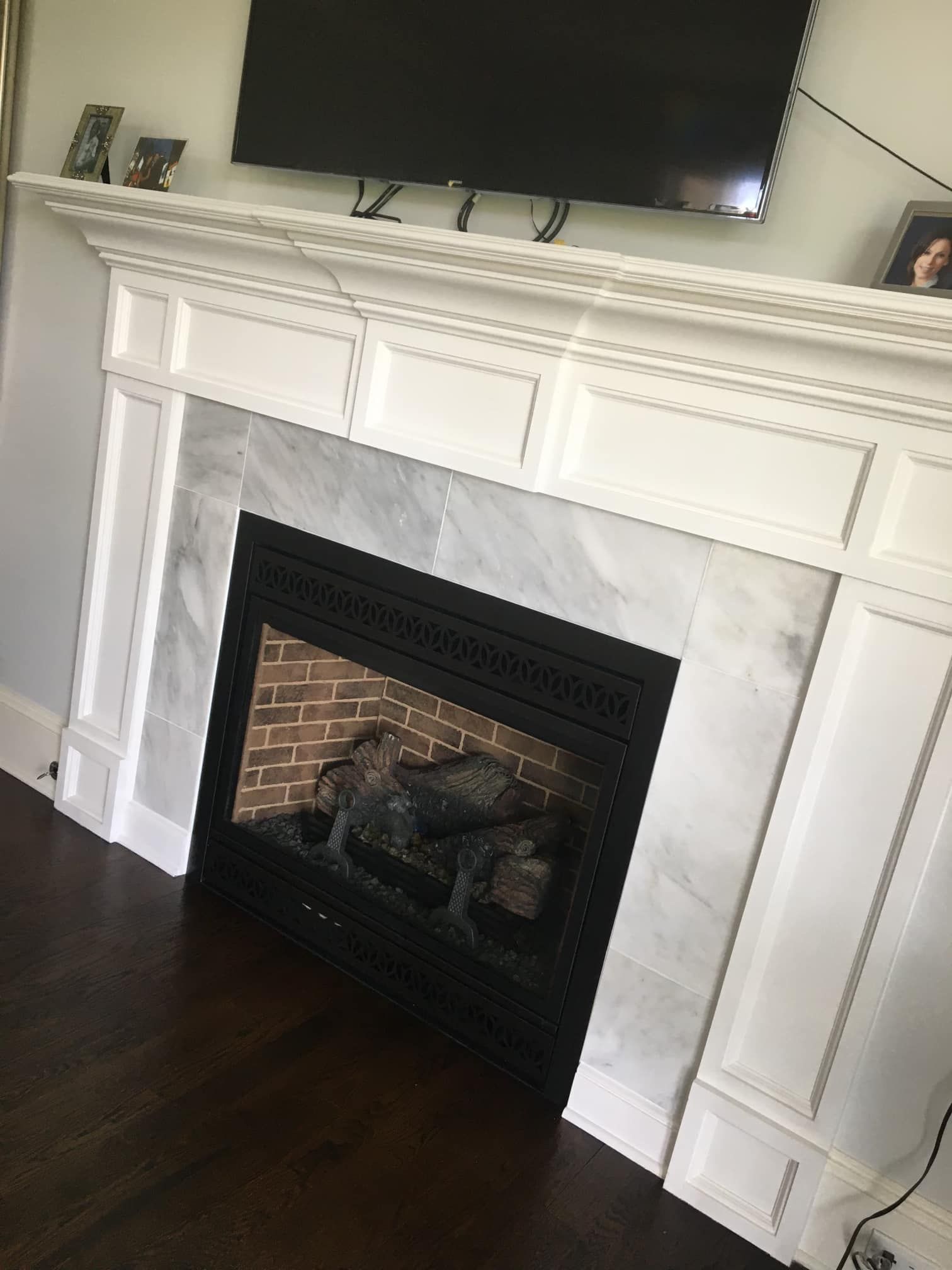 White fireplace with marble surround, black firebox, and a mounted TV.