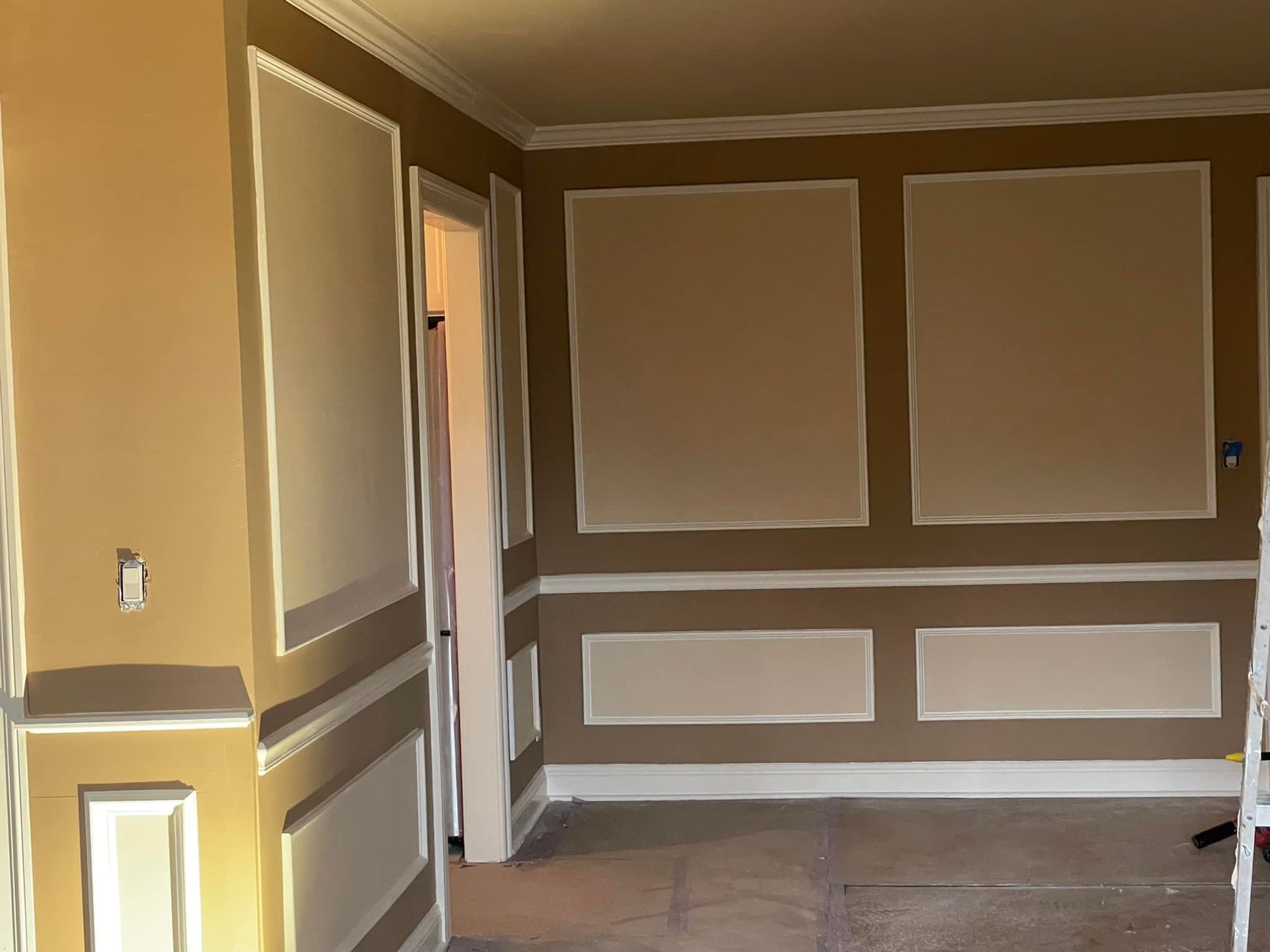 Interior wall with beige paint and white trim, featuring rectangular paneling.