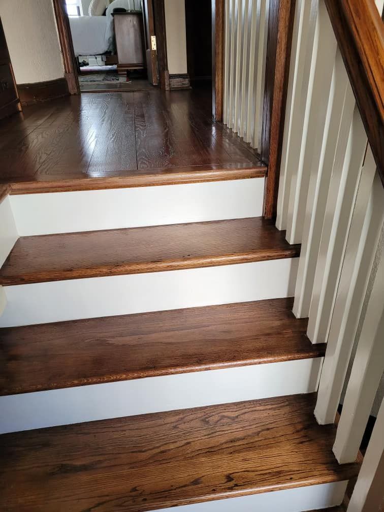 Wooden staircase with white risers and brown treads, leading to a hallway.