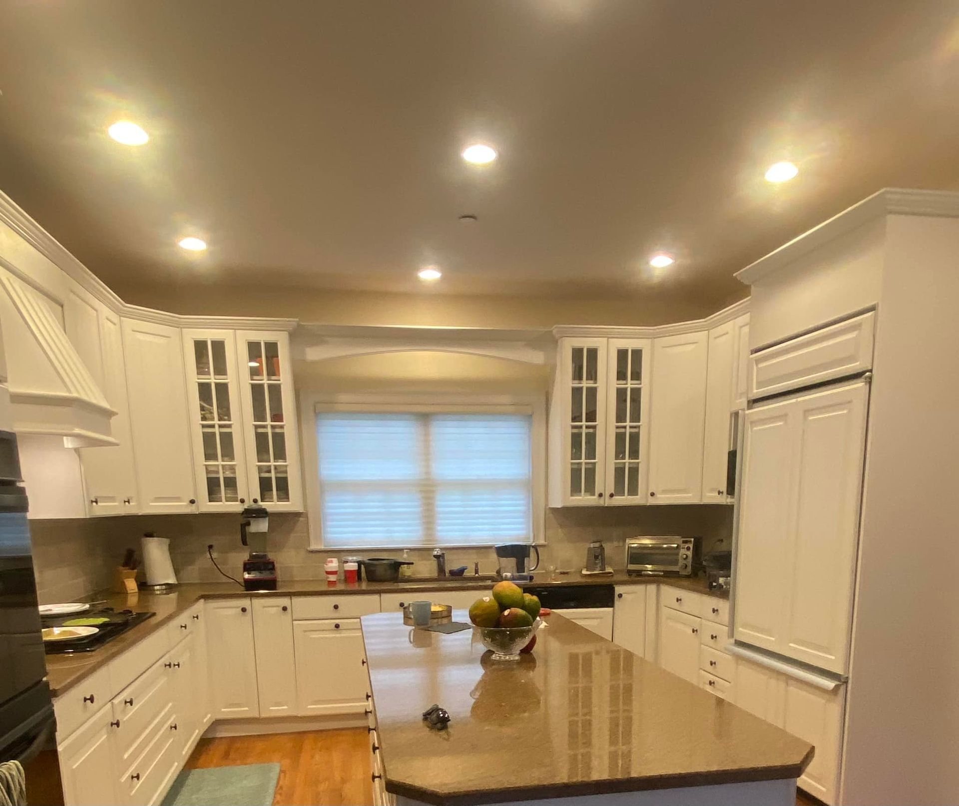 White kitchen with island, cabinets, appliances, and a window.