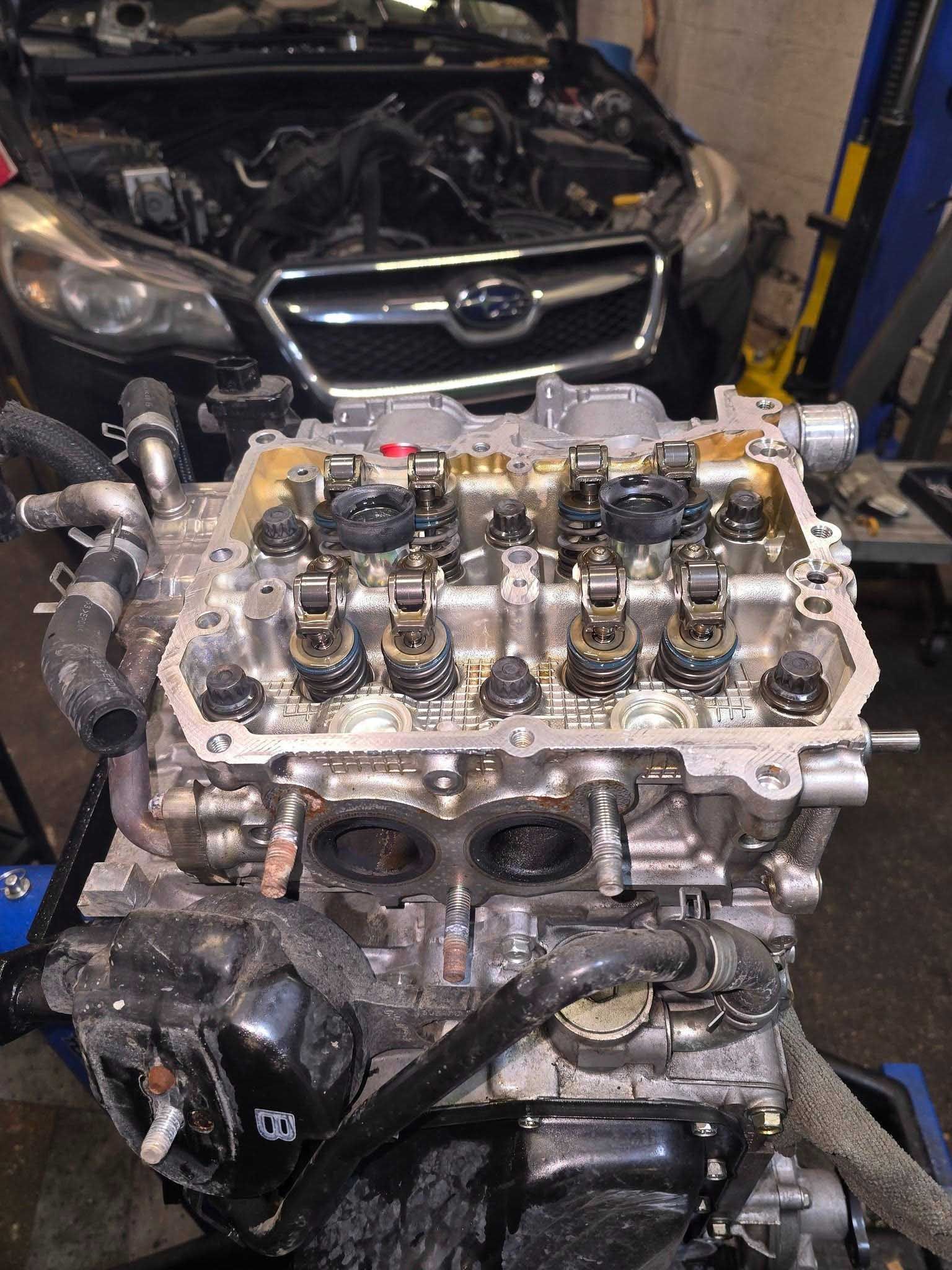 Car engine, removed from vehicle, with visible valves and components, in a garage setting.