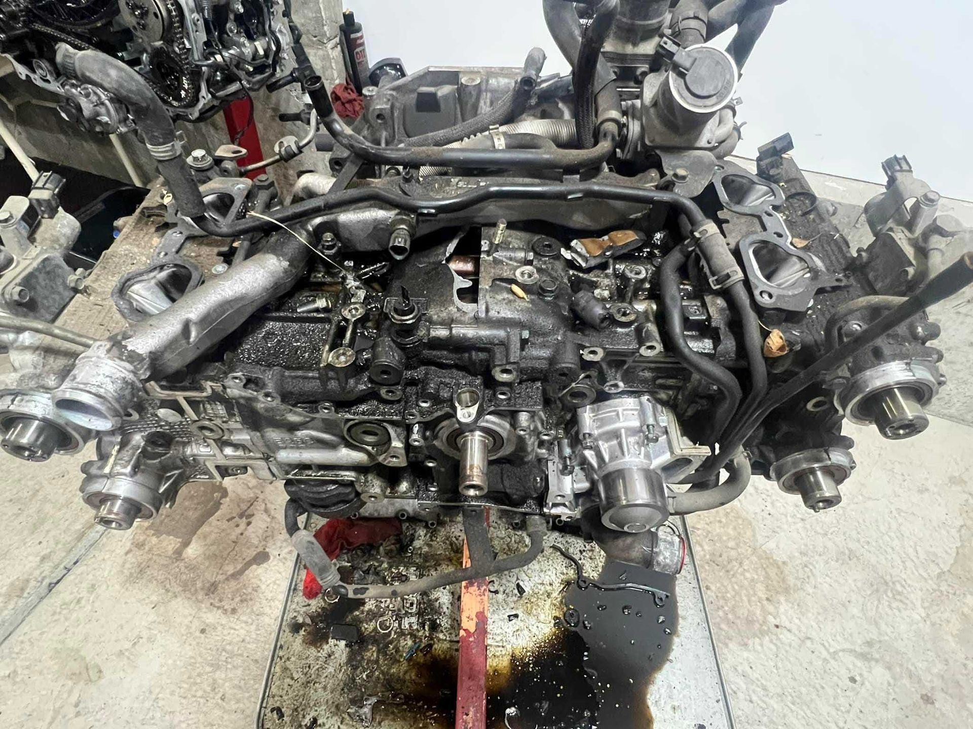 Engine with multiple components, covered in oil, on a workbench.