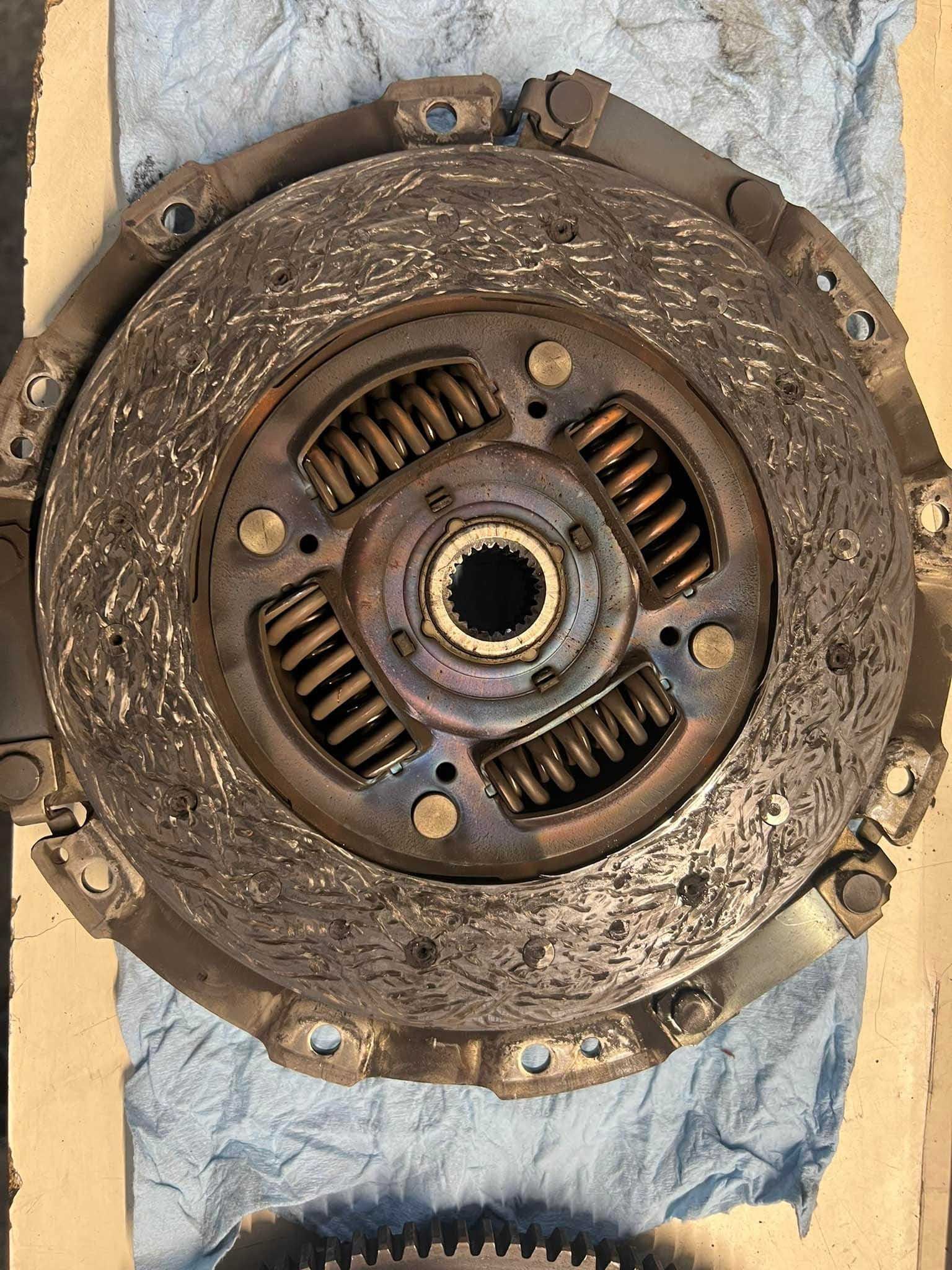 Close-up of a used clutch disc, showing wear and tear, springs, and friction surface.
