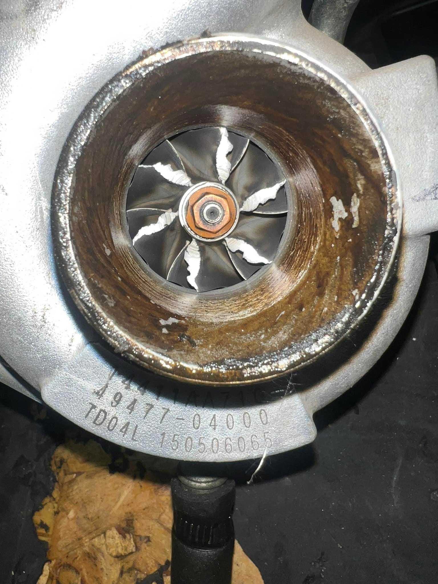Close-up of a turbocharger's impeller and housing. The impeller blades are visible within the housing.